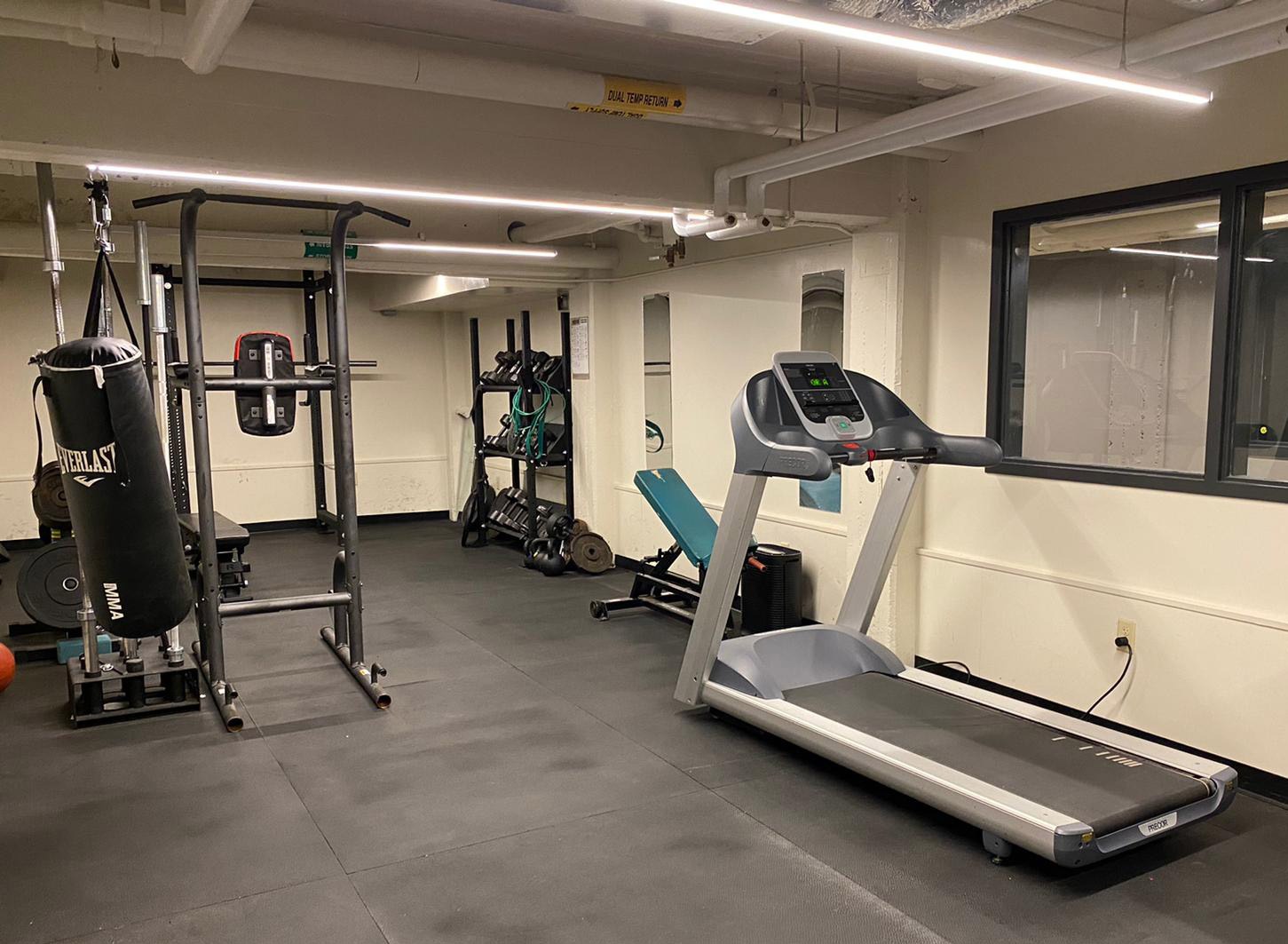 A fitness room with treadmill and weightlifting equipment